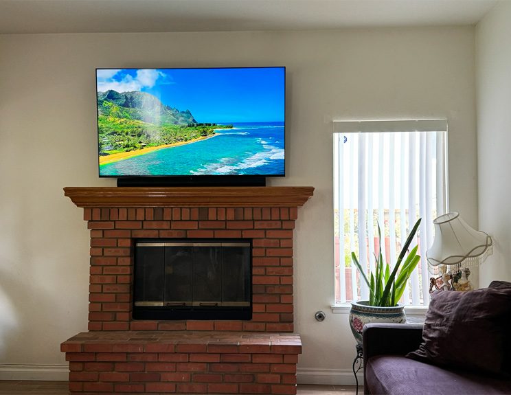 A living room with a fireplace and television mounted on the wall.