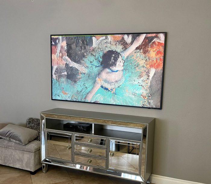 A television mounted on the wall above a mirrored dresser.