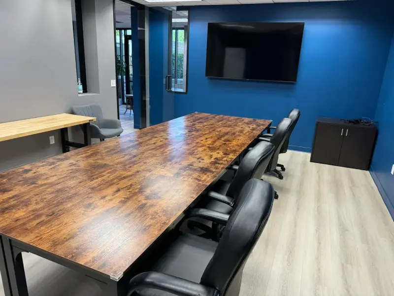 A large table with chairs in front of a flat screen tv.